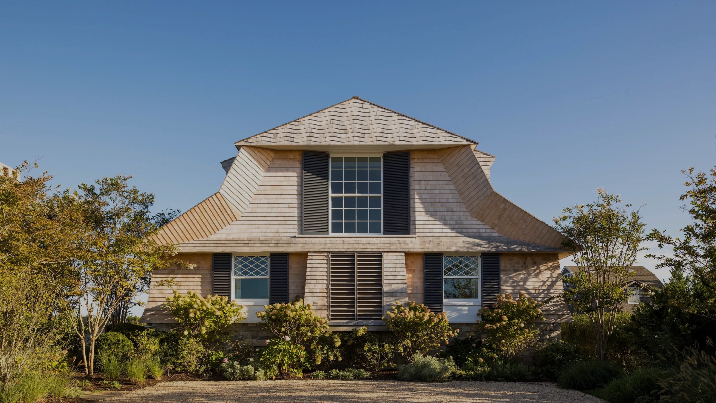 Shingled Hamptons home with a gambrel roof and layered gardens, designed by a TALD architect